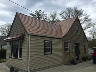 Aged Copper Interlock Slate aluminum roof on a brown Cape Cod home with dormers among tall trees, Milwaukee, Wisconsin