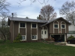 Weathered Interlock Slate aluminum roof on a brown single-storey home with a metal roof among tall, Madison, Wisconsin