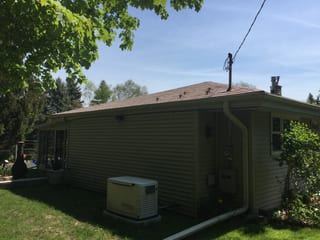 Aged Copper Interlock Slate aluminum roof on a ranch-style home with a metal roof among tall trees in a, Colgate, Wisconsin