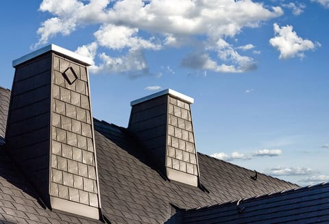 Black aluminum shingle cladding on twin chimneys with a diamond accent