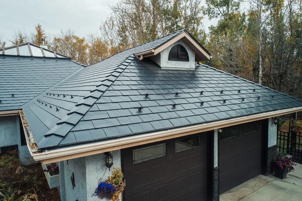 Black Interlock Slate aluminum roof on a black single-family home with dormers among tall trees, Spruce Grove, Alberta