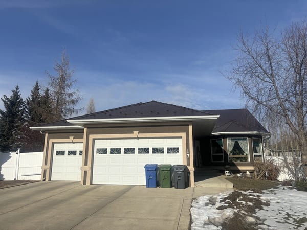 Front elevation of a single-storey ranch home in Red Deer AB featuring Interlock Colonial Brown aluminum slate metal roofing on a multi-hip complex roof.