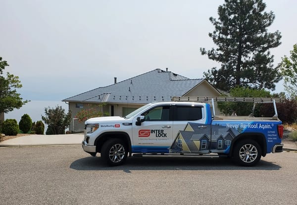 Single-storey ranch home in West Kelowna with Interlock deep charcoal aluminum slate metal roof on a hip structure, with branded truck in foreground.