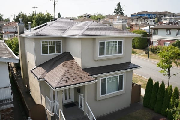 Aerial front view of a 2-storey stucco home in Vancouver with a complex multi-hip Interlock aluminum slate roof in Colonial Brown.