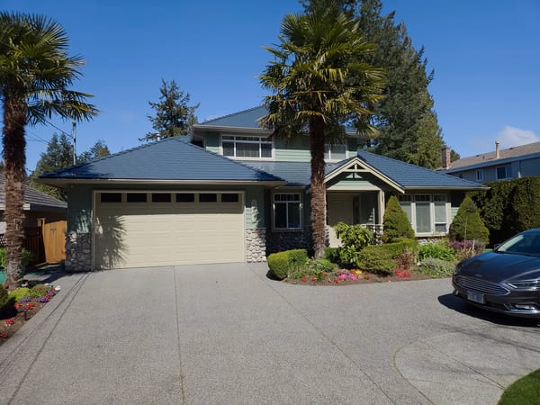 Two-storey Craftsman home in Tsawwassen, BC featuring Interlock deep charcoal aluminum slate roofing across a complex multi-hip roof with stone accents.