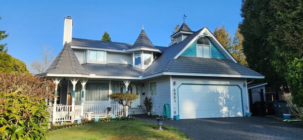 Victorian two-storey home in Surrey BC with Interlock Musket Grey aluminum slate roof featuring turreted peaks, dormers, and a wraparound porch.
