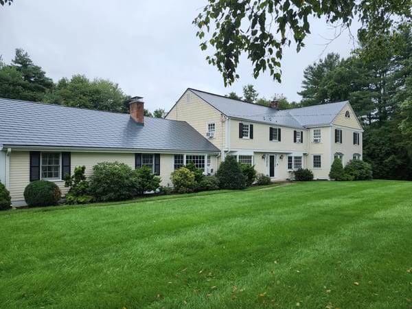 Deep Charcoal Interlock Slate aluminum roof on a two-storey Colonial home with dormers among tall pines, West Simsbury, Connecticut