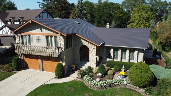 Tudor Brown Interlock Cedar Shingle aluminum roof on a Tudor home with a brown roof among tall trees, Bartlett, Illinois