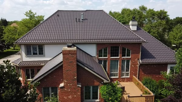 Tudor Brown Interlock Tile aluminum roof on a Tudor style single-family home in a suburban forested, Lemont, Illinois