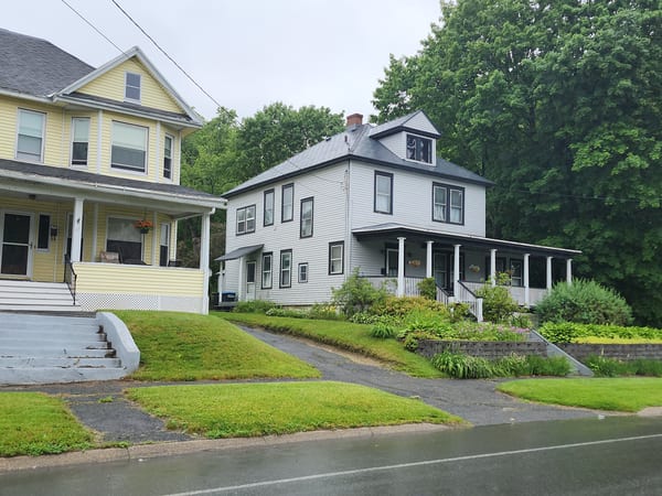 Charcoal grey Interlock aluminum shingle roof on a two-storey white Victorian multi-family home with wrap-around porch and dormer, Pittsfield MA.