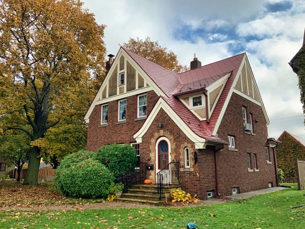 Tile Red Interlock Tile aluminum roof on a brick two-storey home with dormers among tall trees, Saint Paul, Minnesota