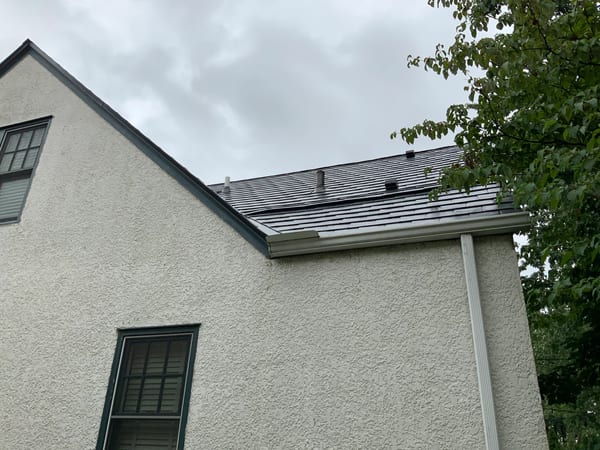 Deep Charcoal Interlock Slate aluminum roof on a white two-storey home with dormers among tall trees, Saint Paul, Minnesota