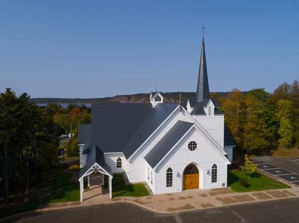 Deep Charcoal Interlock Slate aluminum roof on a white church with a metal roof among tall green trees, Rothesay, New Brunswick