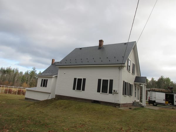 Deep Charcoal Interlock Slate aluminum roof on a white colonial home with dormers on a forested lot, Merrimack, New Hampshire