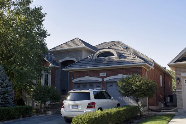 Two-storey brick home in Oakville with a complex multi-hip Interlock aluminum shake roof in Musket Grey, featuring an arched dormer and double garage.