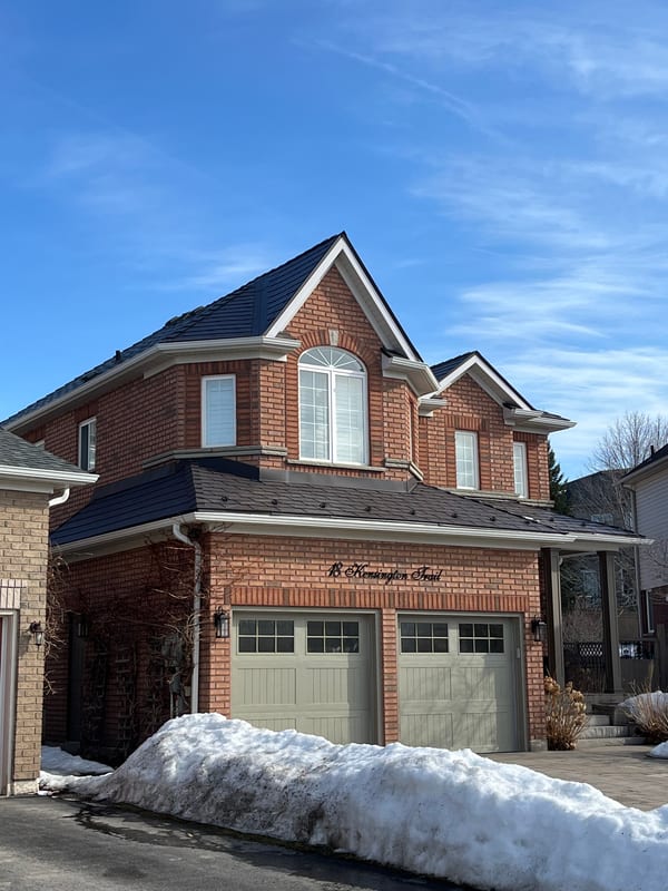 Two-storey brick Colonial home in Barrie, ON featuring Interlock Tudor Brown aluminum slate roofing with complex multi-hip profile and dormers.