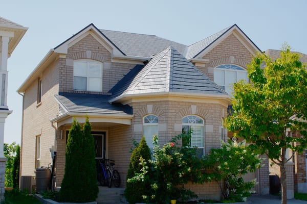 Two-storey brick Colonial home in Milton ON with Interlock deep charcoal aluminum slate roofing featuring a prominent front turret and complex multi-plane roof.