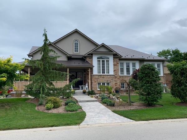 Craftsman-style brick home in Wasaga Beach with Interlock Tudor Brown aluminum slate metal roofing, multi-hip complex roofline, and landscaped front yard.