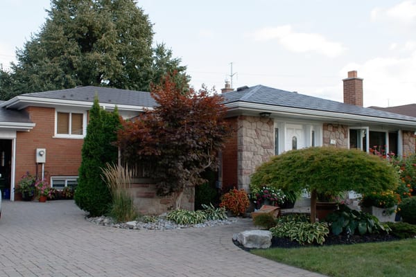 Ranch-style brick and stone home in Scarborough with Interlock Tudor Brown aluminum slate roof, hip profile, brick chimney, and lush landscaped front yard.