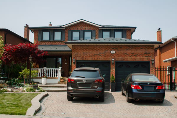 Two-storey brick Colonial home in Woodbridge ON with Interlock deep charcoal aluminum slate roof, dormers, twin chimneys, and double garage.