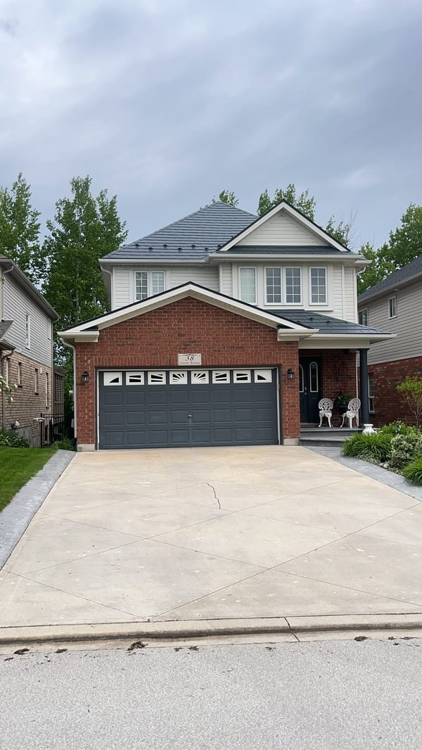 Two-storey brick home in Collingwood, ON with Interlock deep charcoal aluminum slate metal roofing on a multi-hip complex roof profile.