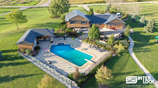 Aerial view of a large rural single-family home in Fenwick, ON featuring Interlock Deep Charcoal aluminum slate roofing across a complex multi-hip roof with a pool.