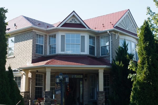 Two-storey Victorian-style brick home in Oakville with complex multi-gable Tile Red Interlock aluminum slate metal roofing and covered front entry porch.