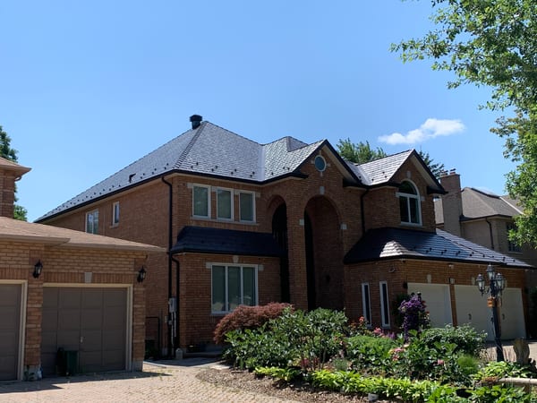 Tudor-style brick home in Richmond Hill with complex multi-hip Interlock aluminum cedar shingle roof in Tudor Brown, featuring valleys, dormers, and arched entryway.