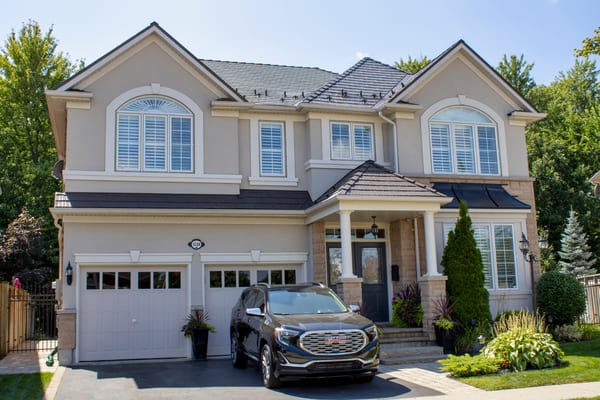 Two-storey Colonial home in Milton ON with Interlock Tudor Brown cedar shingle metal roofing, multi-hip complex roof, and covered front portico.