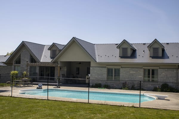 Rear elevation of a large Craftsman-style home in Guelph, ON featuring Interlock Musket Grey cedar shingle metal roofing with multiple dormers and louvered vents.
