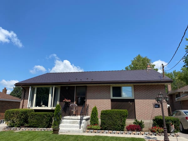Single-storey ranch-style brick home in Belleville, ON, with a low-pitch Interlock aluminum slate roof in Colonial Brown under a bright blue sky.