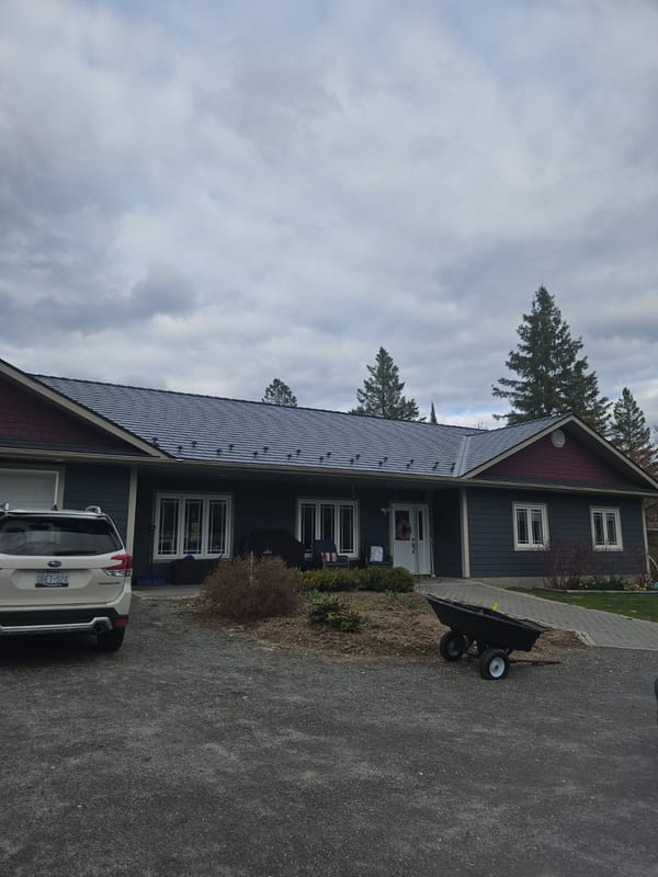 Front elevation of a single-storey ranch home in Sudbury, ON featuring Interlock deep charcoal cedar shingle aluminum metal roofing with snow guards.