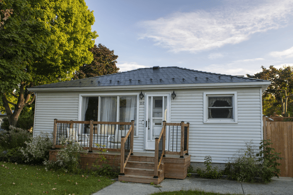 Single-storey ranch-style home in Kingston ON with a low-pitch hip roof clad in deep charcoal Interlock aluminum slate tiles and a new cedar front deck.