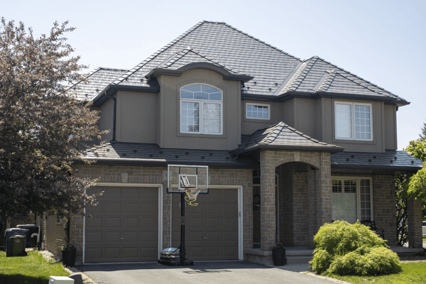 Two-storey suburban home in Guelph ON with complex multi-hip Interlock Tudor Brown aluminum slate metal roofing featuring a central dormer and stone facade.