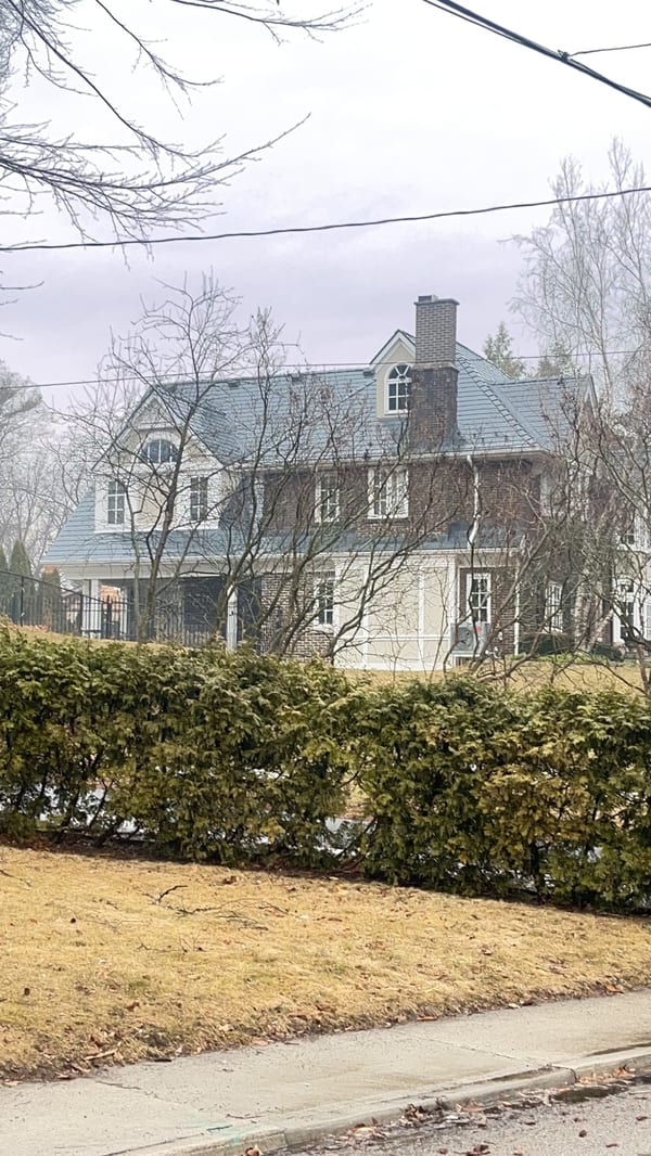 Two-storey colonial brick home in Burlington ON with steep deep charcoal Interlock aluminum slate roof, twin dormers, and brick chimney, viewed from street.