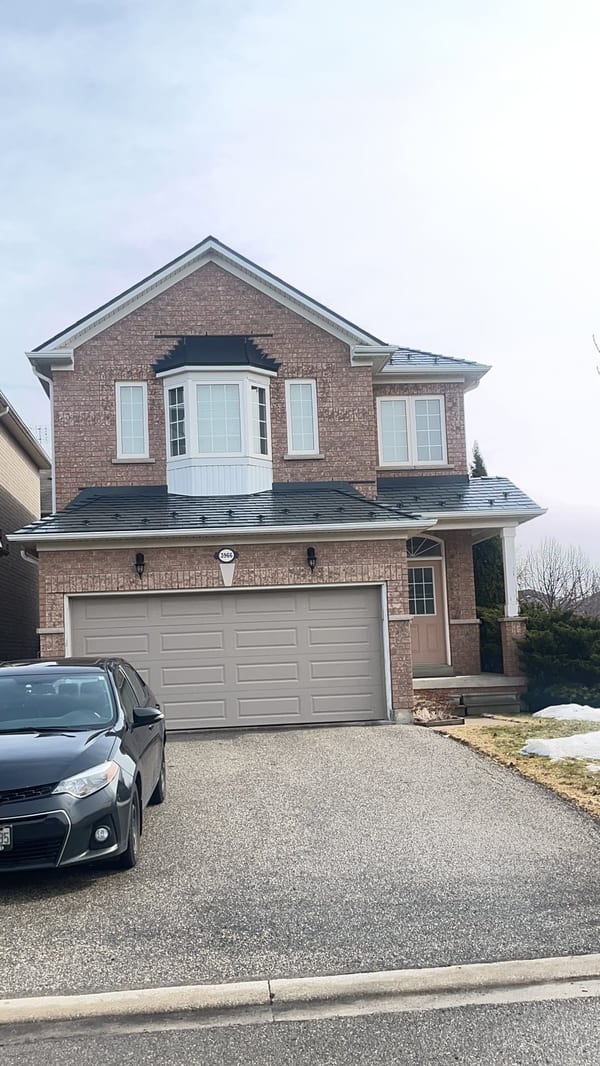 Two-storey brick home in Mississauga with Interlock deep charcoal aluminum slate metal roofing covering a multi-plane complex roof with bay window.