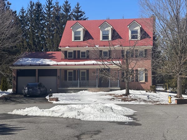Aged Copper Interlock Shingle aluminum roof on a two-storey red brick home with a metal roof and snow on, Stittsville, Ontario