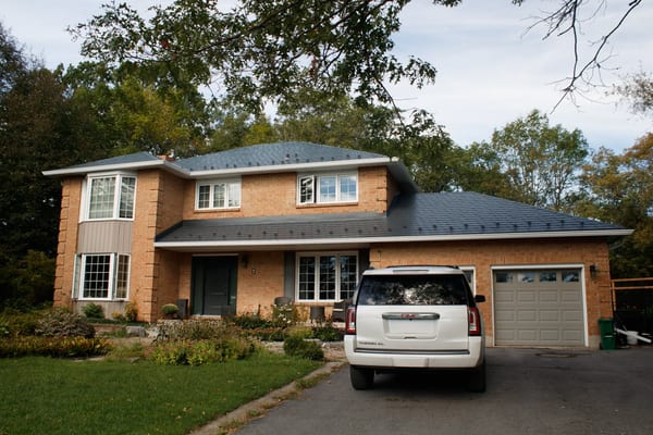 Two-storey brick Colonial home in Kingston, ON featuring an Interlock deep charcoal aluminum slate hip roof with clean lines and attached two-car garage.