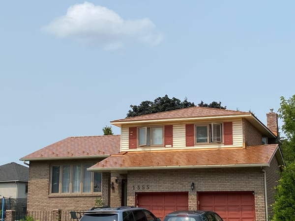 Two-storey Colonial brick home at 1355 with Interlock Copper Penny aluminum slate metal roof, red shutters, and double garage in Gloucester, ON.
