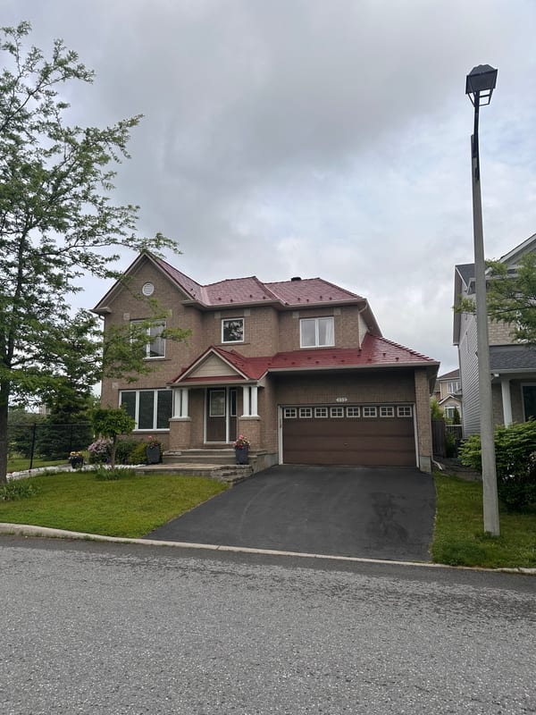 Two-storey brick Colonial home in Ottawa with a multi-hip Interlock aluminum slate roof in Tile Red, featuring a double garage and covered entry.