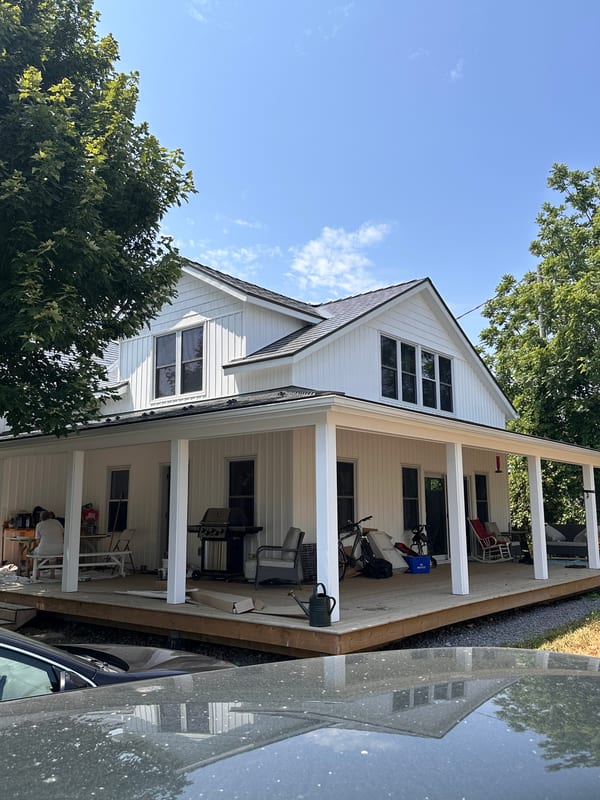 Modern farmhouse in Bloomfield ON with Interlock Musket Grey aluminum slate roofing, wraparound porch, and dormer windows.