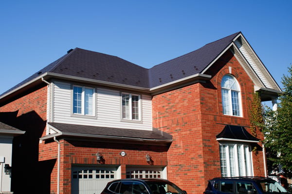Two-storey brick home in Richmond Hill with complex multi-hip Interlock Tudor Brown aluminum shingle roof, arched window, and double garage.