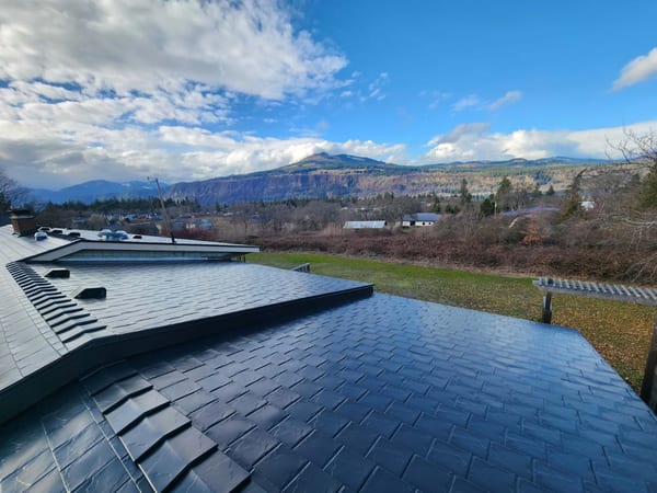 Black Interlock aluminum slate metal roofing on a modern home in Hood River, OR, with mountain and gorge views beyond.