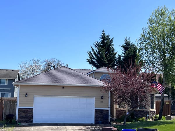 Tudor Brown Interlock aluminum cedar shingle metal roof on a 1.5-story hip-roofed suburban home in Molalla, OR, with stone veneer accents.