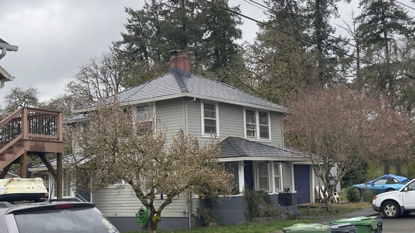 Two-story craftsman home in St. Helens OR featuring Interlock black aluminum slate metal roofing with hip roof and brick chimney.