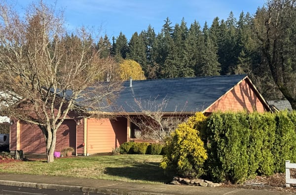 Single-story Ranch home in Silverton, OR with Interlock deep charcoal aluminum slate metal roof, gable profile, and attached two-car garage amid fall foliage.