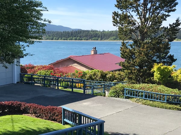 Single-story ranch home with Interlock Tile Red aluminum slate metal roof and chimney, set on a waterfront hillside in Anacortes, WA.