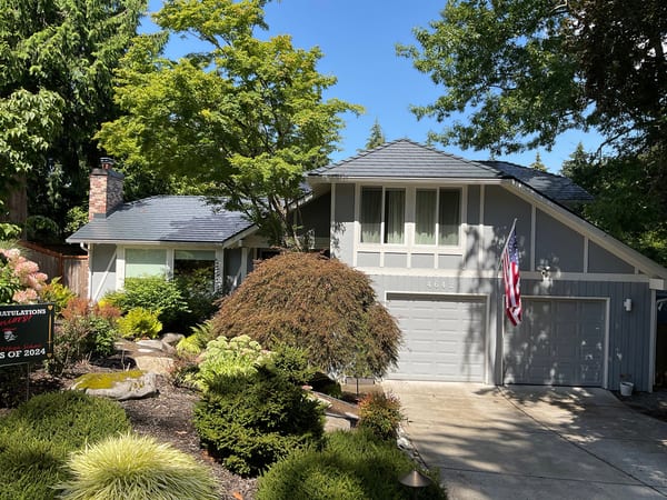 Front elevation of a grey Craftsman home in Bellevue, WA featuring Interlock Deep Charcoal aluminum slate metal roofing on a multi-hip complex roof.