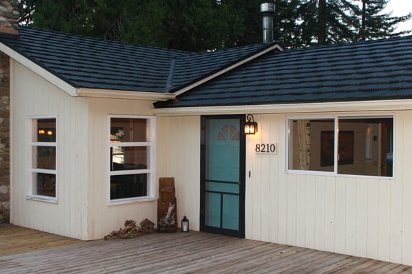 Black Interlock Shake aluminum roof on a white one-storey home with a dark roof among tall pines, Shelton, Washington