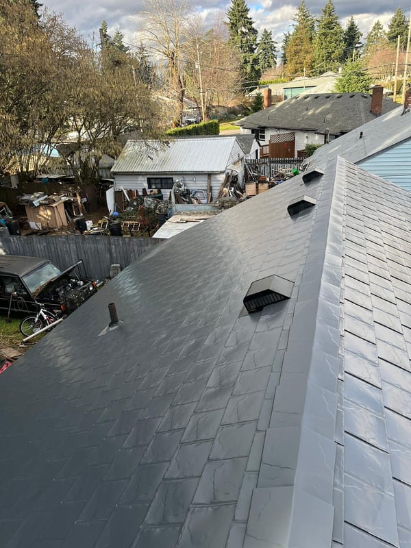 Aerial rear view of Interlock deep charcoal aluminum slate metal roof with roof louvers and vent pipe on a suburban ranch-style home in Vancouver, WA.